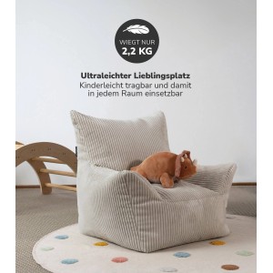 Beiger mokebo Kindersessel aus Cord mit Dino-Kuscheltier auf Punkteteppich.