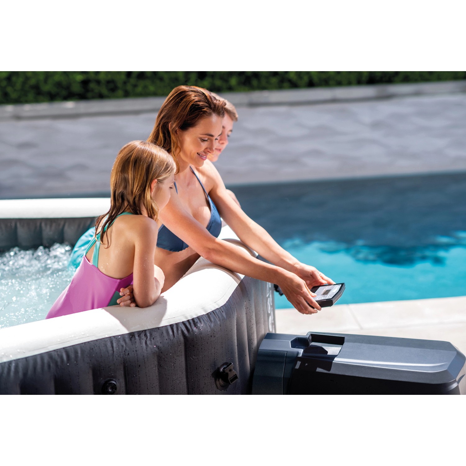 Intex PureSpa Octagon aufblasbarer Whirlpool mit Familie im Garten, Bedienfeld in der Hand.