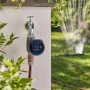Gardena Smart Sensor Control Set am Wasserhahn mit Rasensprenger im Hintergrund.