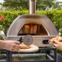 Buschbeck Pizzaofen X1 mit Pizzaschieber beim Pizzabacken im Garten.