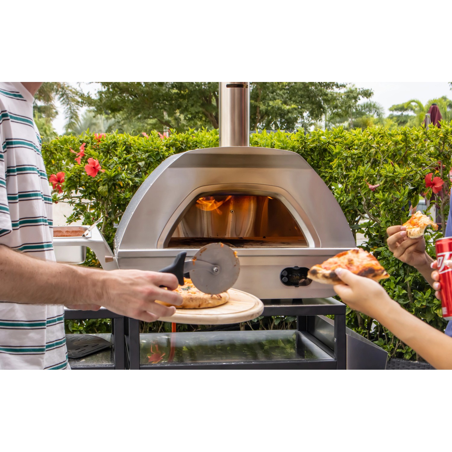 Buschbeck Pizzaofen X1 mit Pizzaschieber beim Pizzabacken im Garten.