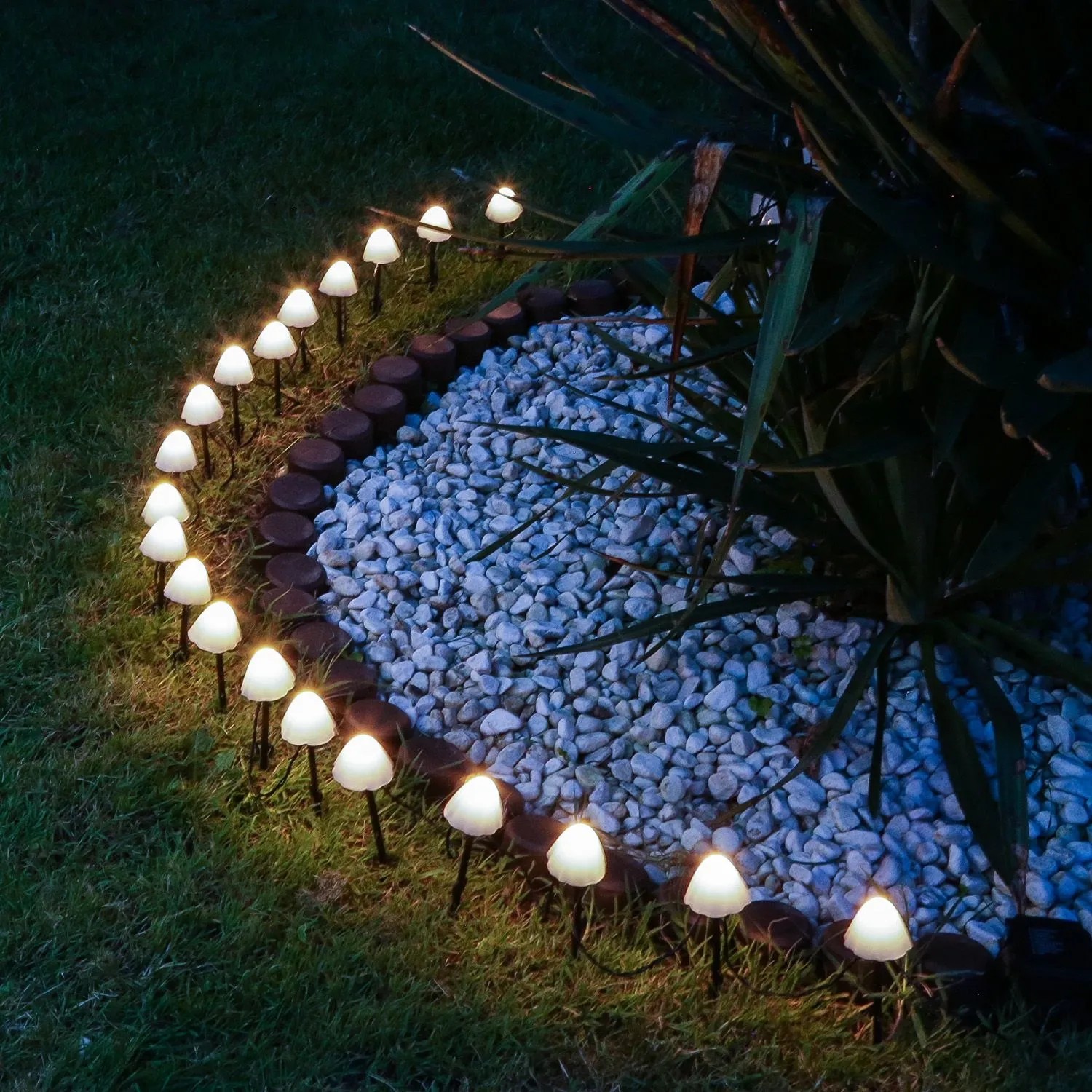 Marelida LED Solar Lichterkette mit 10 leuchtenden Mini Pilzen als Gartenstecker im dunklen Gartenbeet.