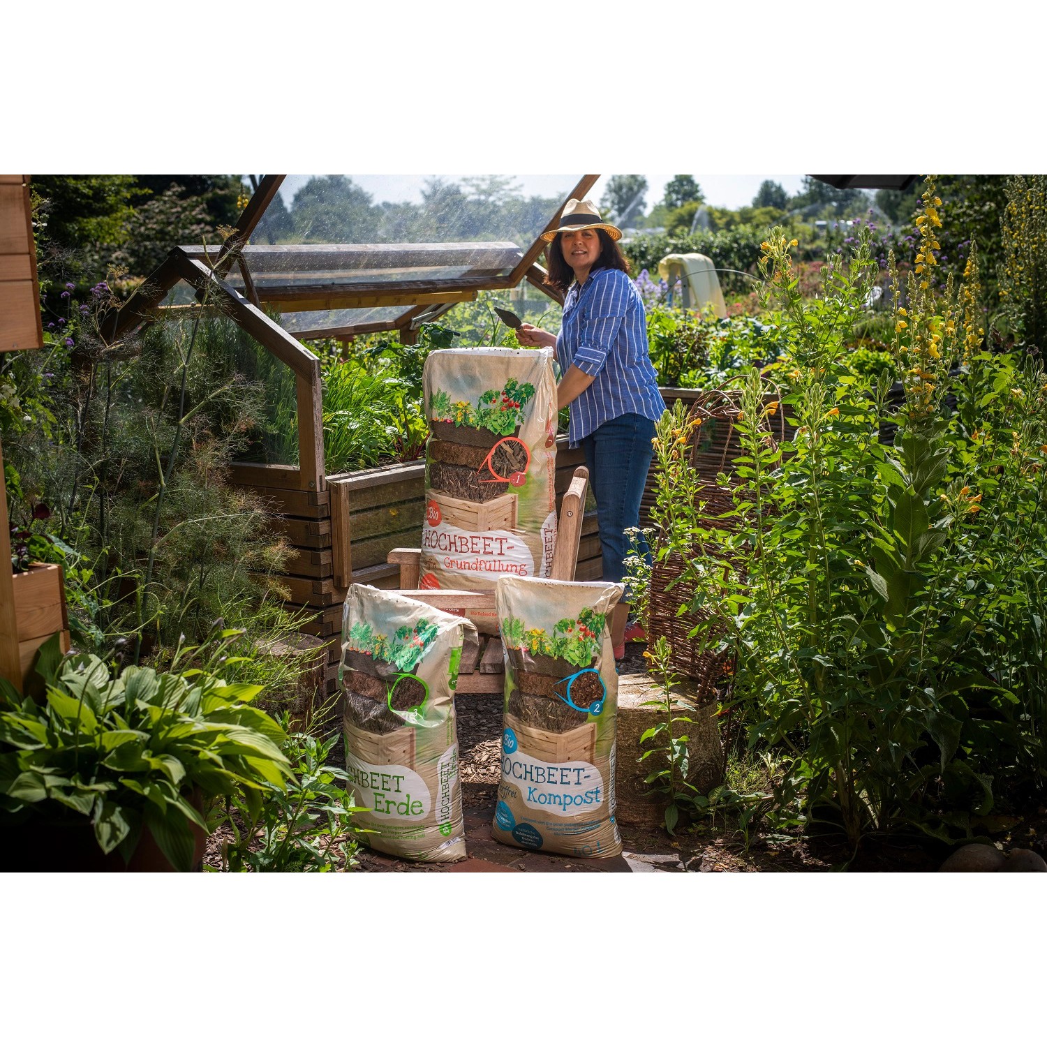 Floragard Hochbeeterde-Kompost (1200 l) mit Frau im Garten und Hochbeet im Hintergrund.