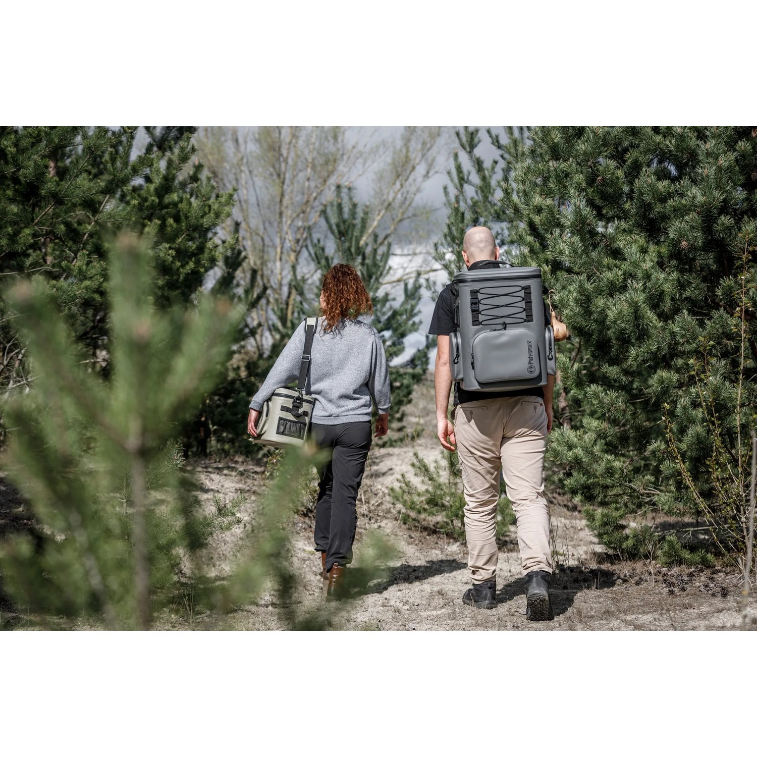 Personen mit Petromax Kühlrucksack, Kühlbox und Isolierflasche im Wald.