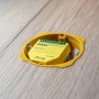 Gelber Shelly Controller RGBW Plus PM für Hausautomation, eingebaut in eine Holzwand.