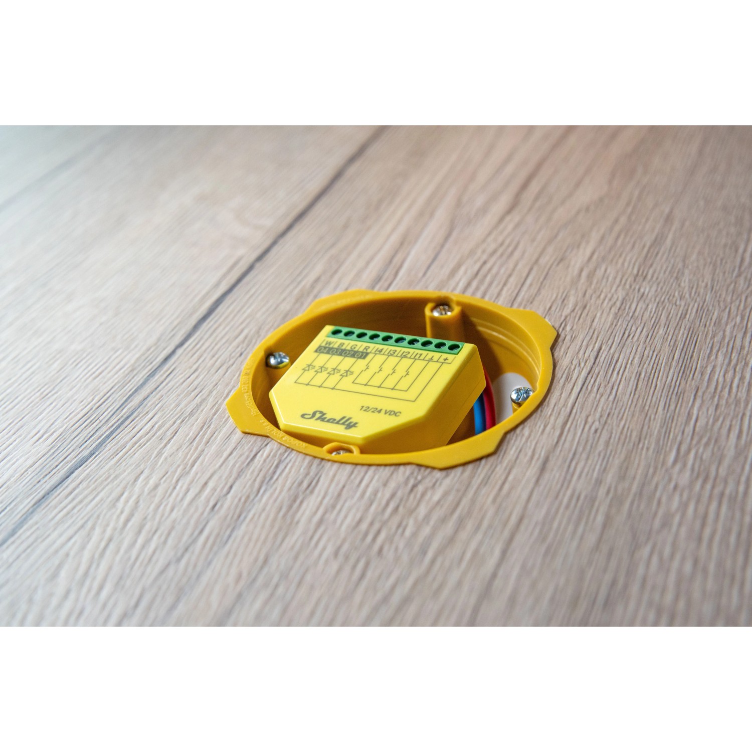 Gelber Shelly Controller RGBW Plus PM für Hausautomation, eingebaut in eine Holzwand.