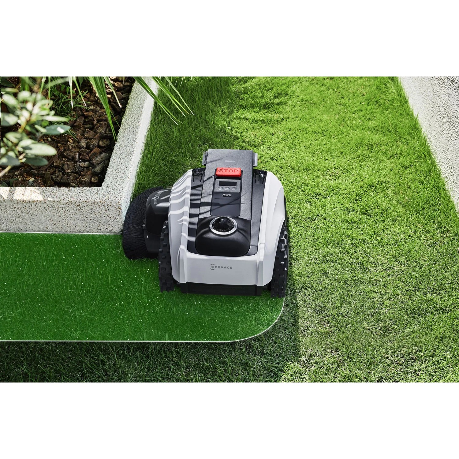 Ecovacs Mähroboter Goat O1200 auf Rasen, weiß-schwarz, mit Kantenschneider.