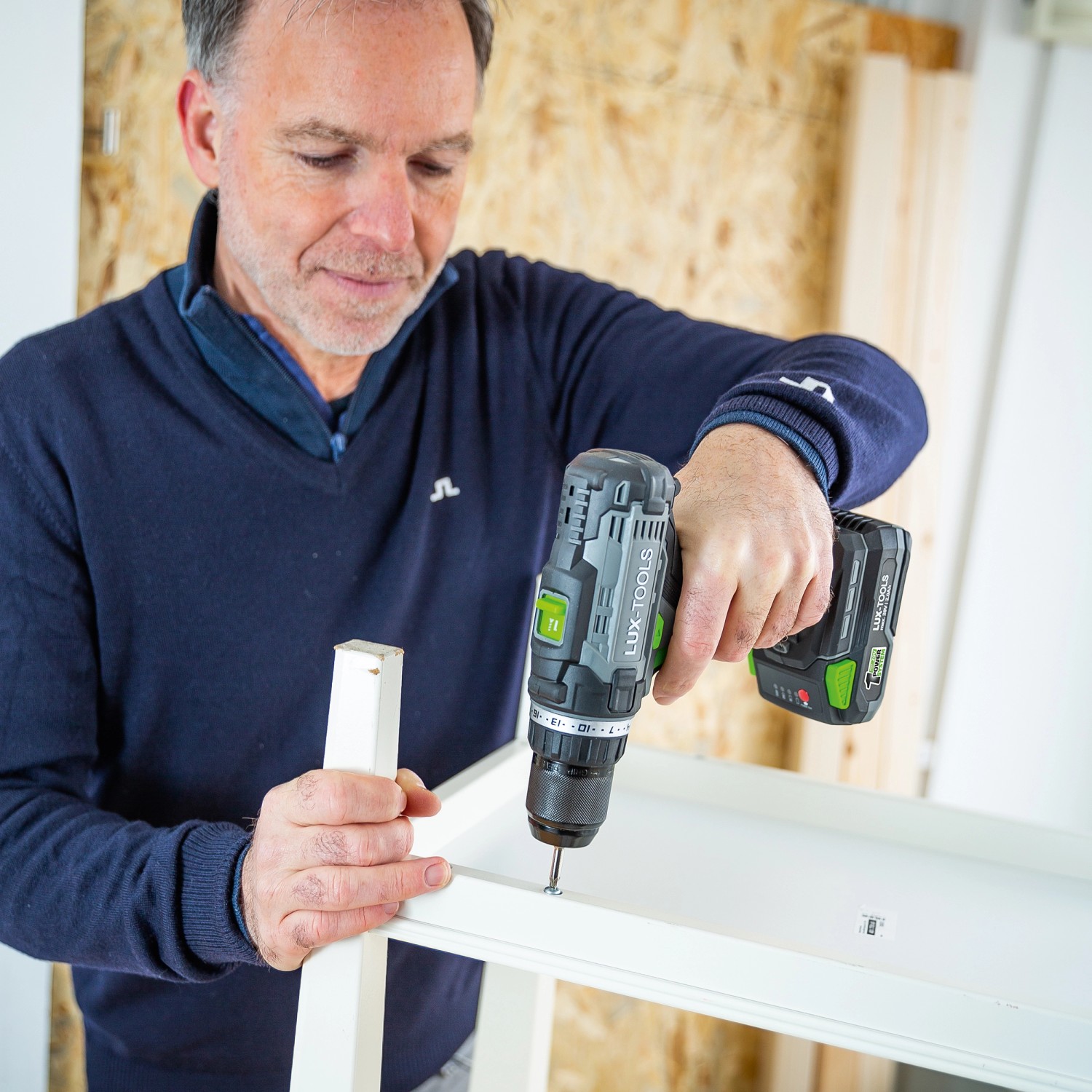 Mann schraubt mit LUX Akku-Bohrschrauber A-BS-20 ein Möbelstück zusammen.
