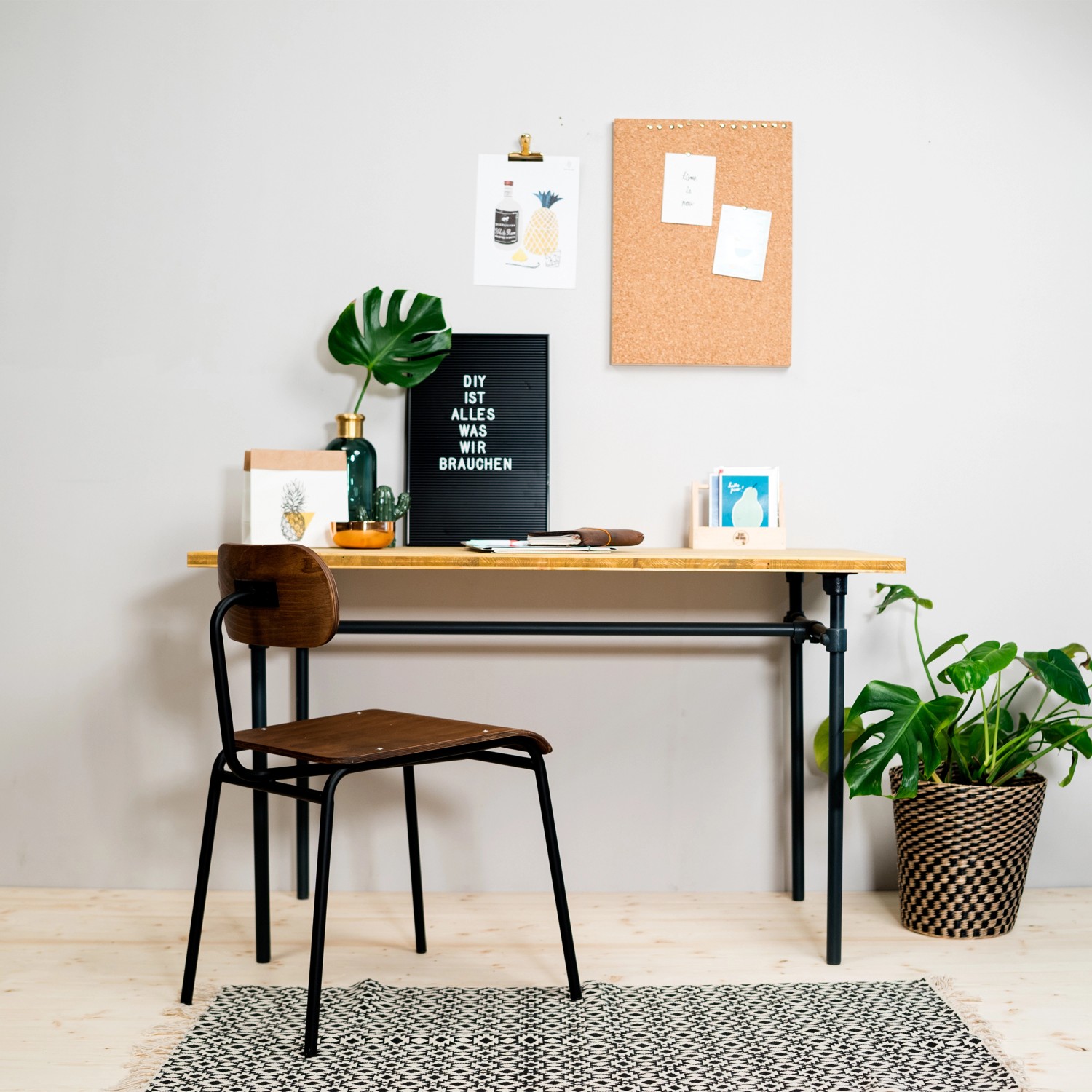 DIY-Tisch mit Stahlrohr-Gestell (schwarz matt) und Holzplatte, kombiniert mit Stuhl und Dekoration.