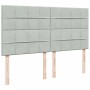 Hellgraues Boxspringbett Kopfteil mit Samtbezug und Holzfüßen.