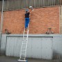 Krause Schiebeleiter Stabilo 2-teilig im Einsatz: Mann auf Aluleiter vor Backsteinmauer.