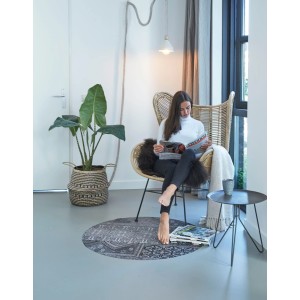 Runder Teppich Smuq Nepal Ø 100 cm im Wohnzimmer mit Frau im Sessel. Gemusterter Vinylteppich.