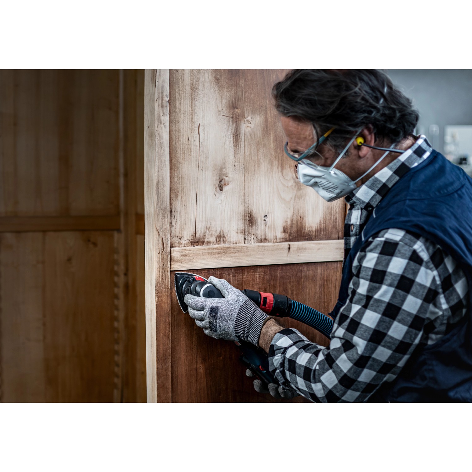 Mann schleift Holzschrank mit Bosch Deltaschleifer und Schleifblatt C470 K80.