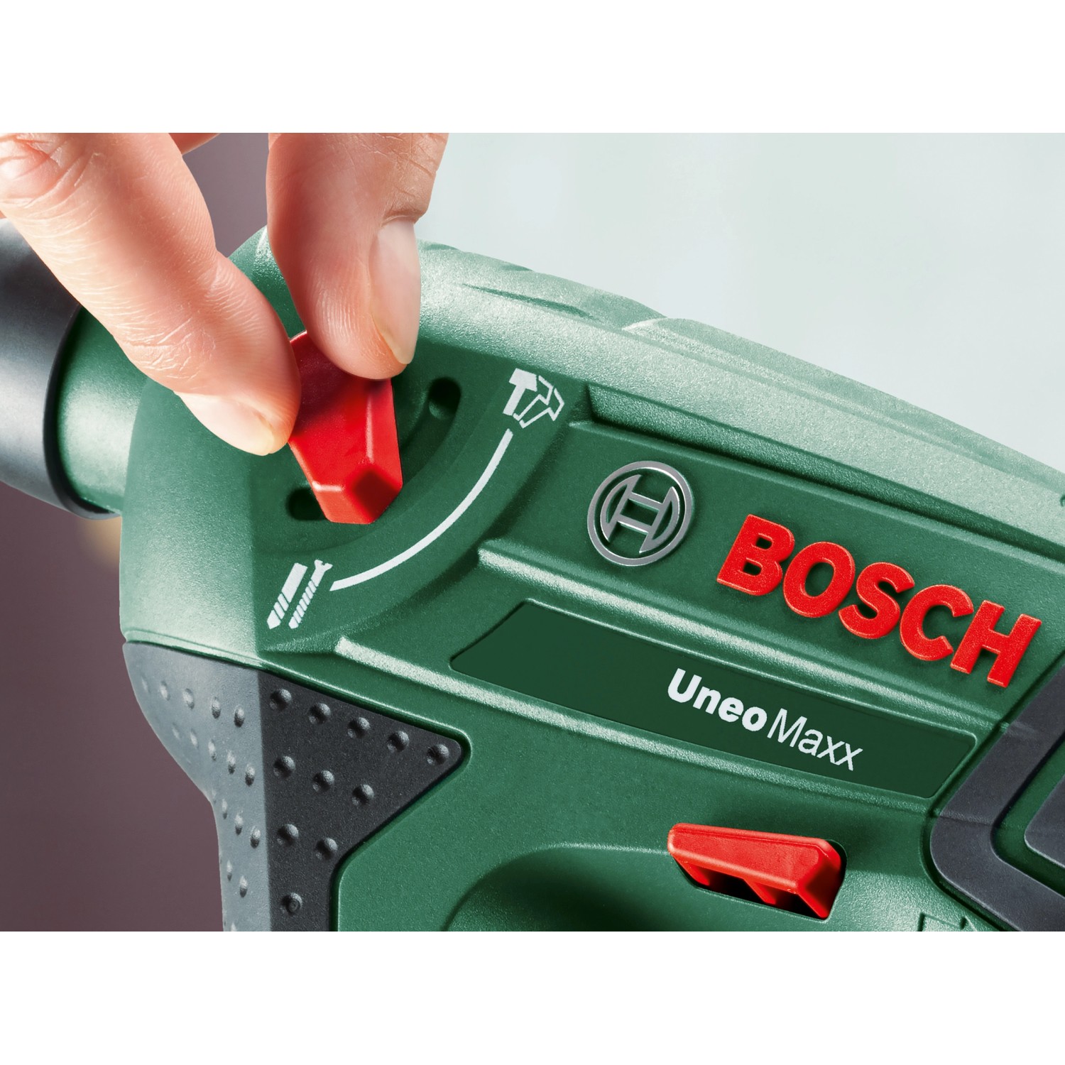Detailaufnahme: Hand bedient Schalter am grünen Bosch Uneo Maxx Akku-Bohrhammer.