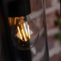 Schwarze, eckige Lutec Solar-Wandleuchte Flair mit klarem Zylinder und warmweißer Glühbirne.