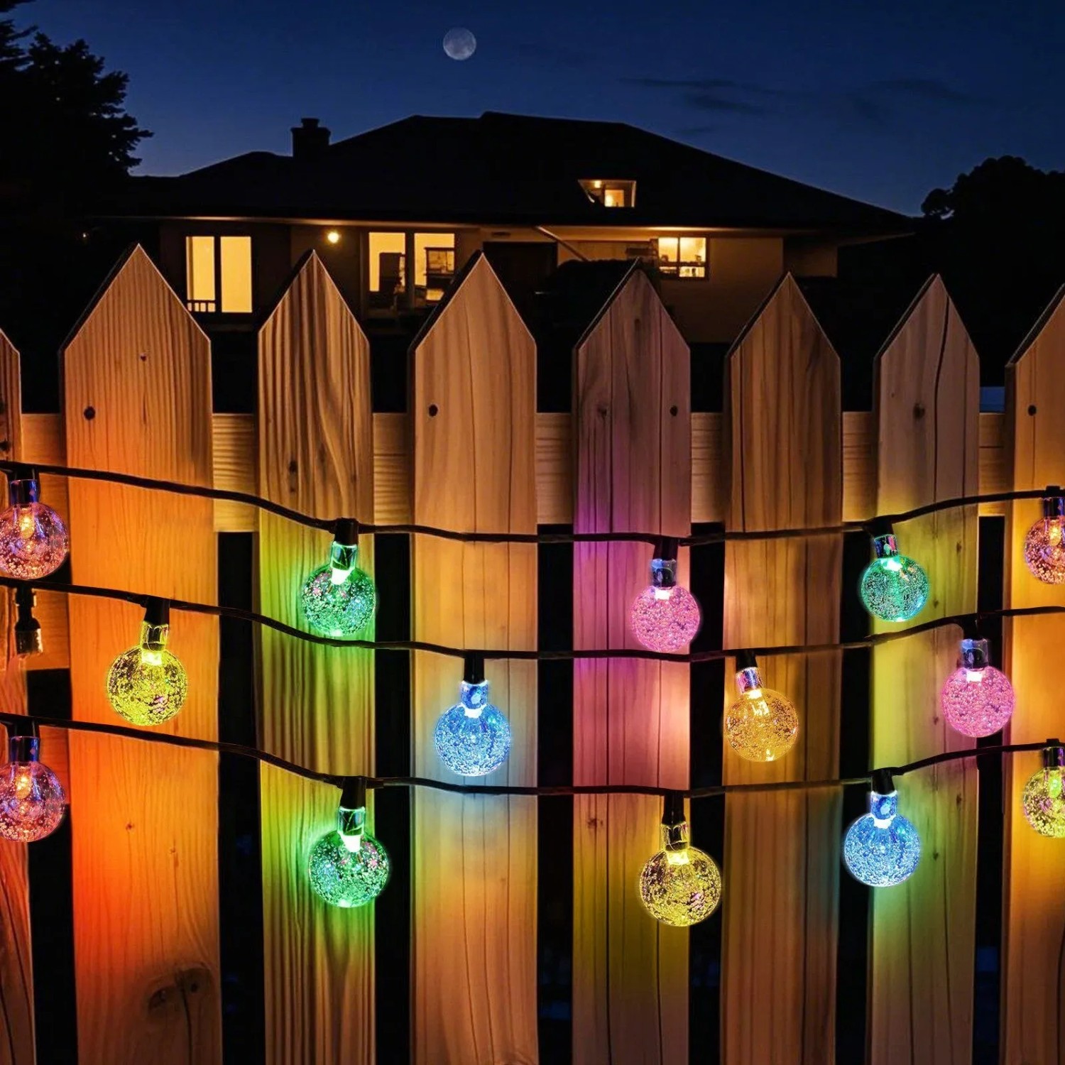 Bunte Solar LED Lichterkette mit 40 Kristalllampen am Holzzaun bei Nacht. Ideal für Garten & Weihnachtsbeleuchtung.