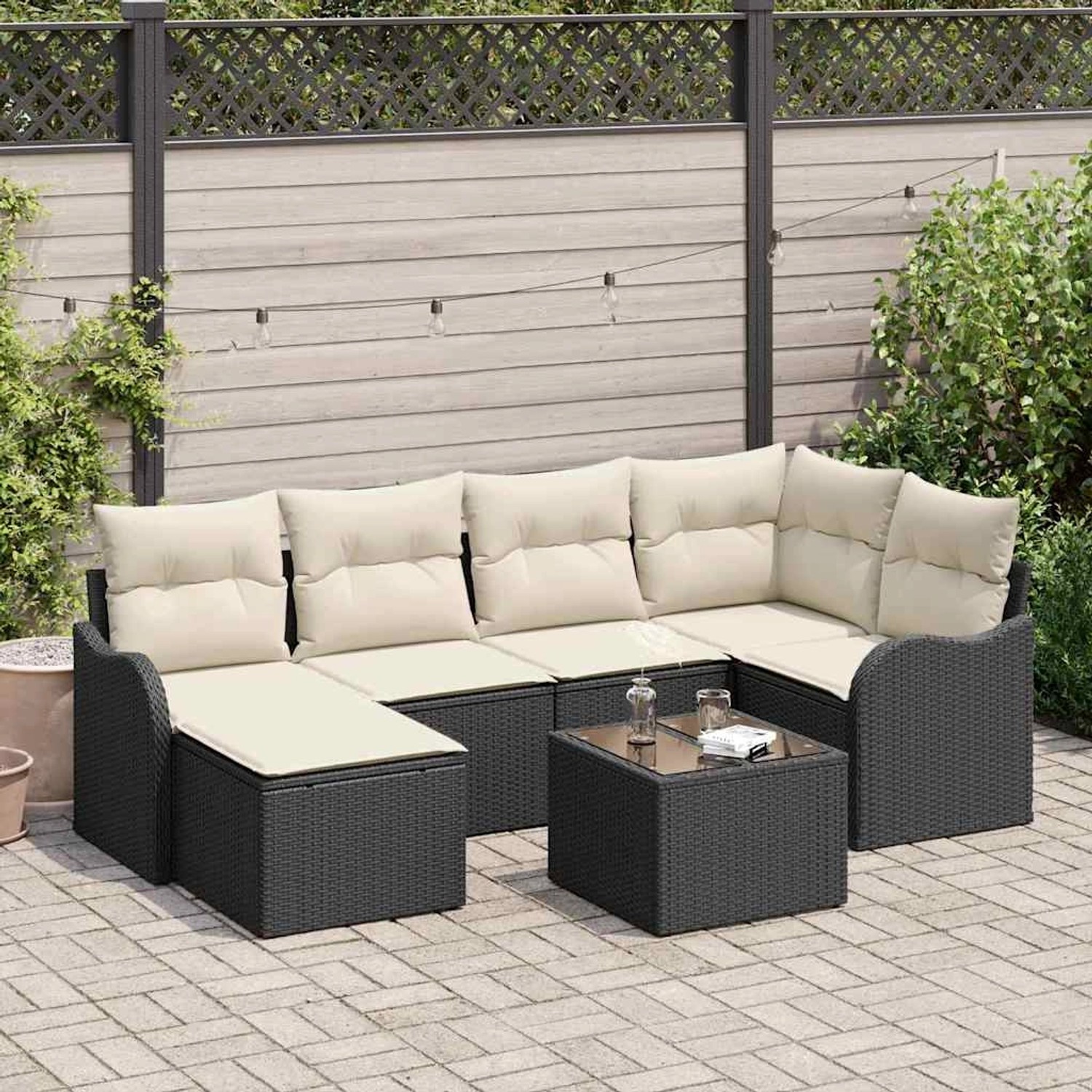 Schwarzes 7-teiliges vidaXL Garten-Sofa-Set aus Poly Rattan mit weißen Kissen und Tisch.