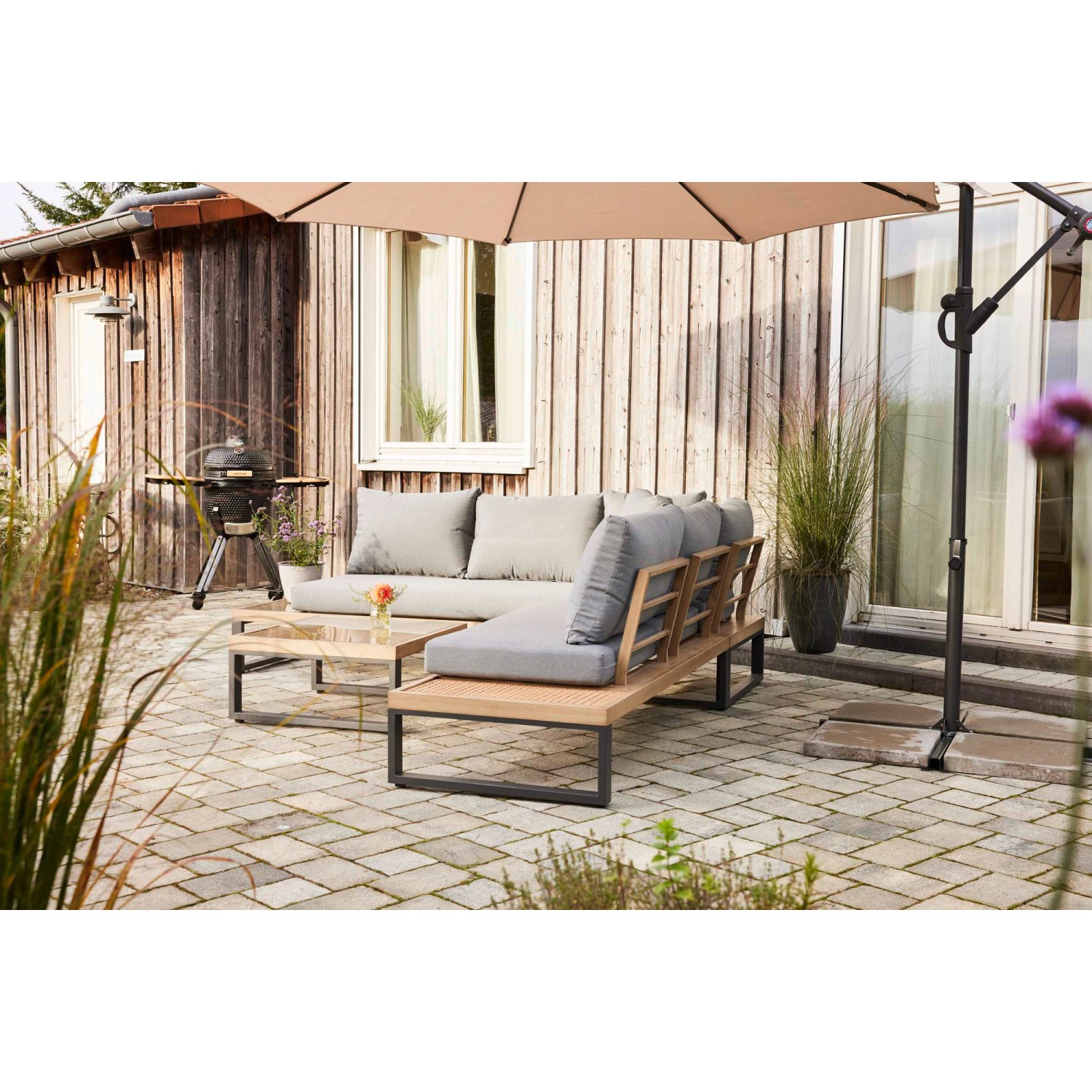 3-teiliges Lounge-Set Calora aus Rattangeflecht und Aluminium in Grau mit Tisch und hellgrauen Kissen.