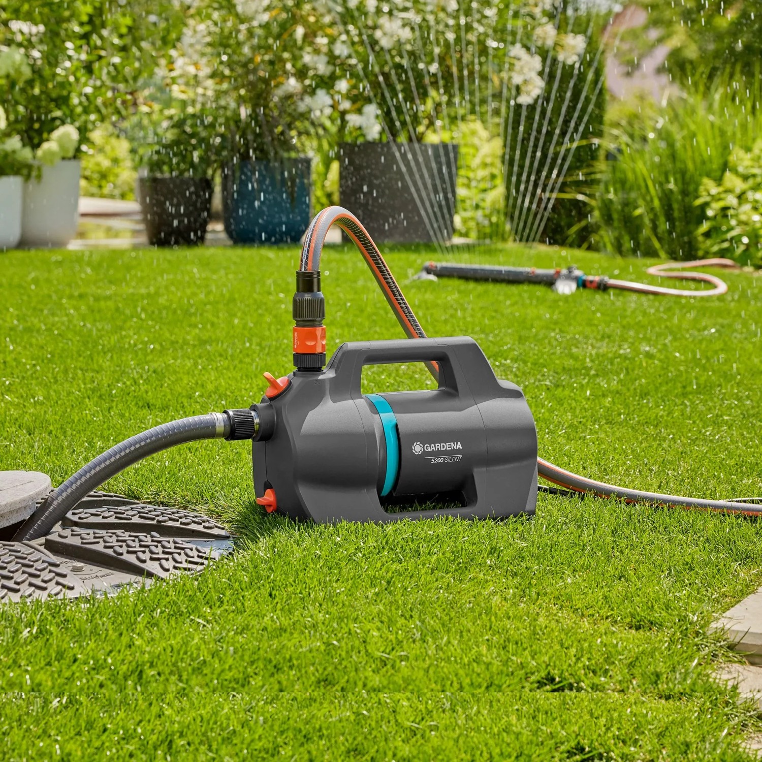 Gardena Gartenpumpe 5200 Silent Set mit Schlauch und Sauggarnitur im Einsatz auf Rasen.