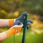 Hände mit LUX Super Grip Arbeitshandschuhen Gr. 10 beim Drahtziehen an einem Zaunpfahl.