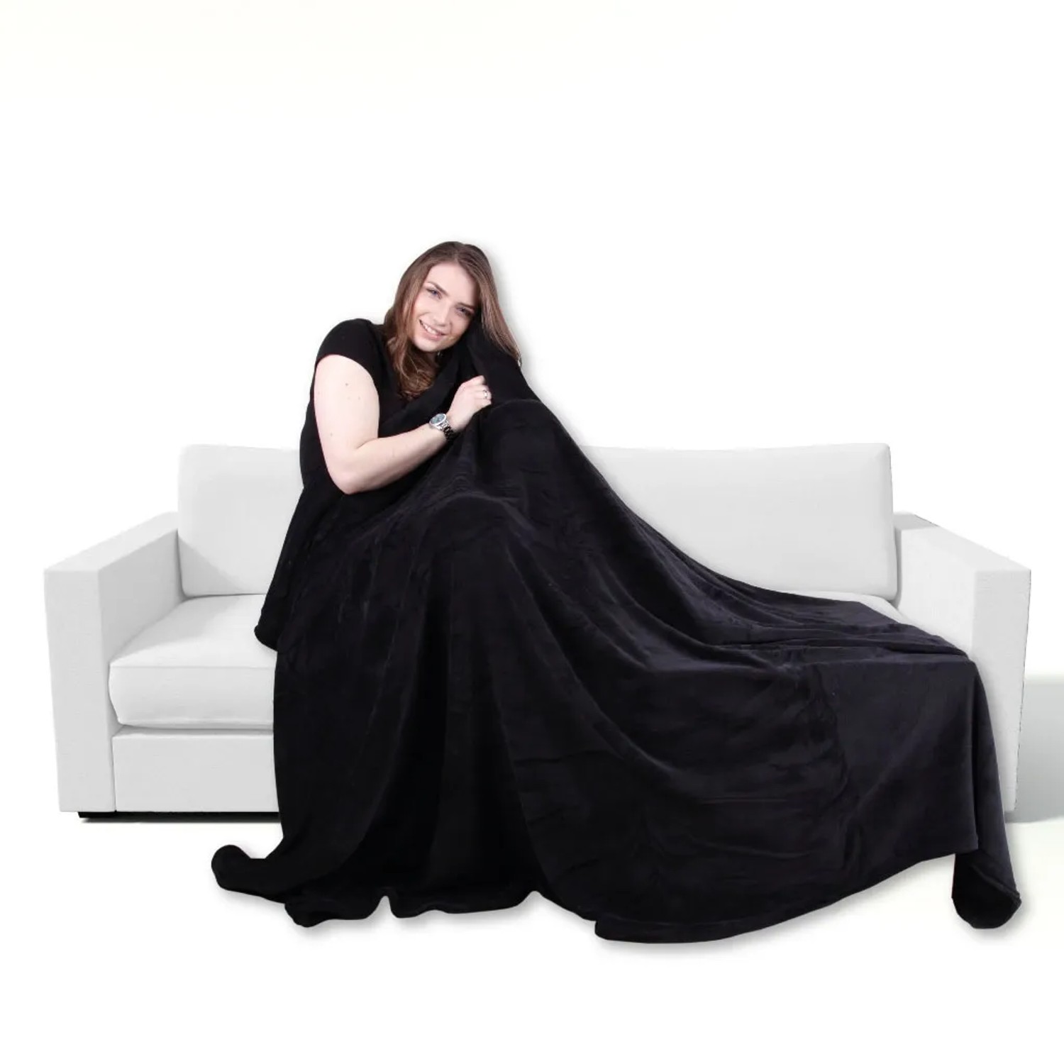 Frau kuschelt in schwarze Mikrofaser Decke (150x200 cm) auf weißem Sofa. Bestgoodies Wohndecke.