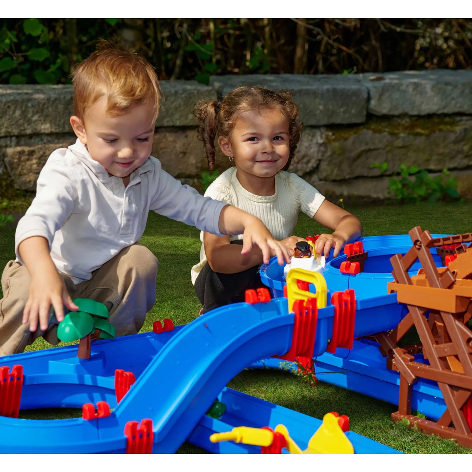 Kinder spielen mit AquaPlay WaterWheel Wasserbahn (53-teilig) im Garten.