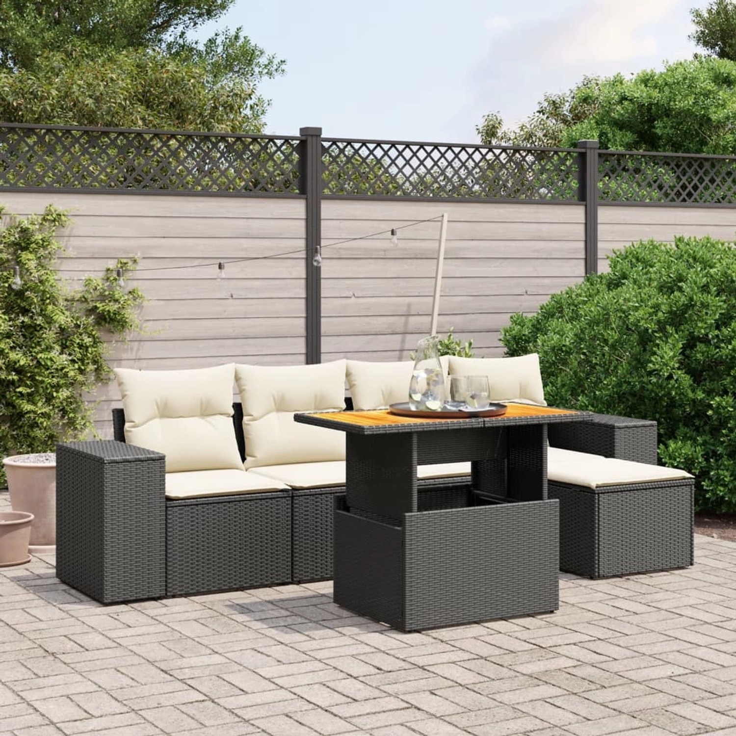 Schwarze 6-tlg. Garten-Sofagarnitur aus Rattan mit Tisch und cremefarbenen Kissen.