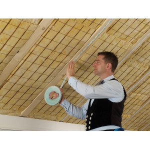 Handwerker befestigt Siga Twinet Dämmstoffzubehör an einer Dachsparre.