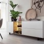 Modernes Sideboard in Weiß mit schwarzen Füßen, dekoriert mit Pflanzen und Wandbild.