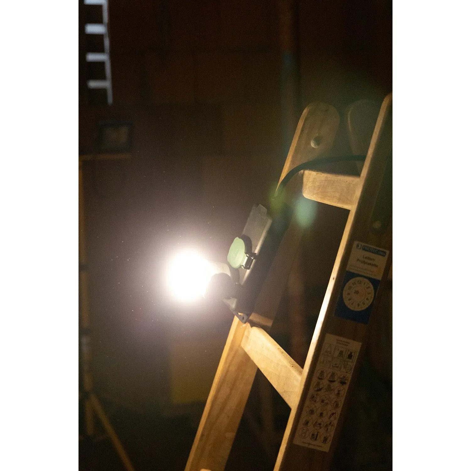 REV Ritter LED-Steckdosenstrahler (10W, dimmbar) an einer Holzleiter.
