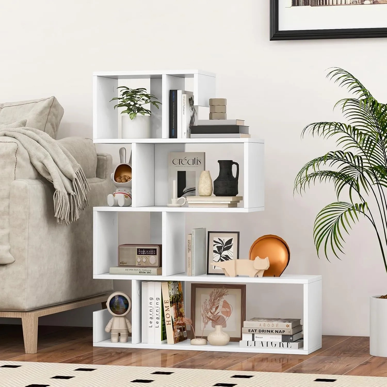 Modernes, weißes Costway Bücherregal mit 5 S-förmigen Ebenen, gefüllt mit Büchern, Pflanzen und Deko, im Wohnzimmer.
