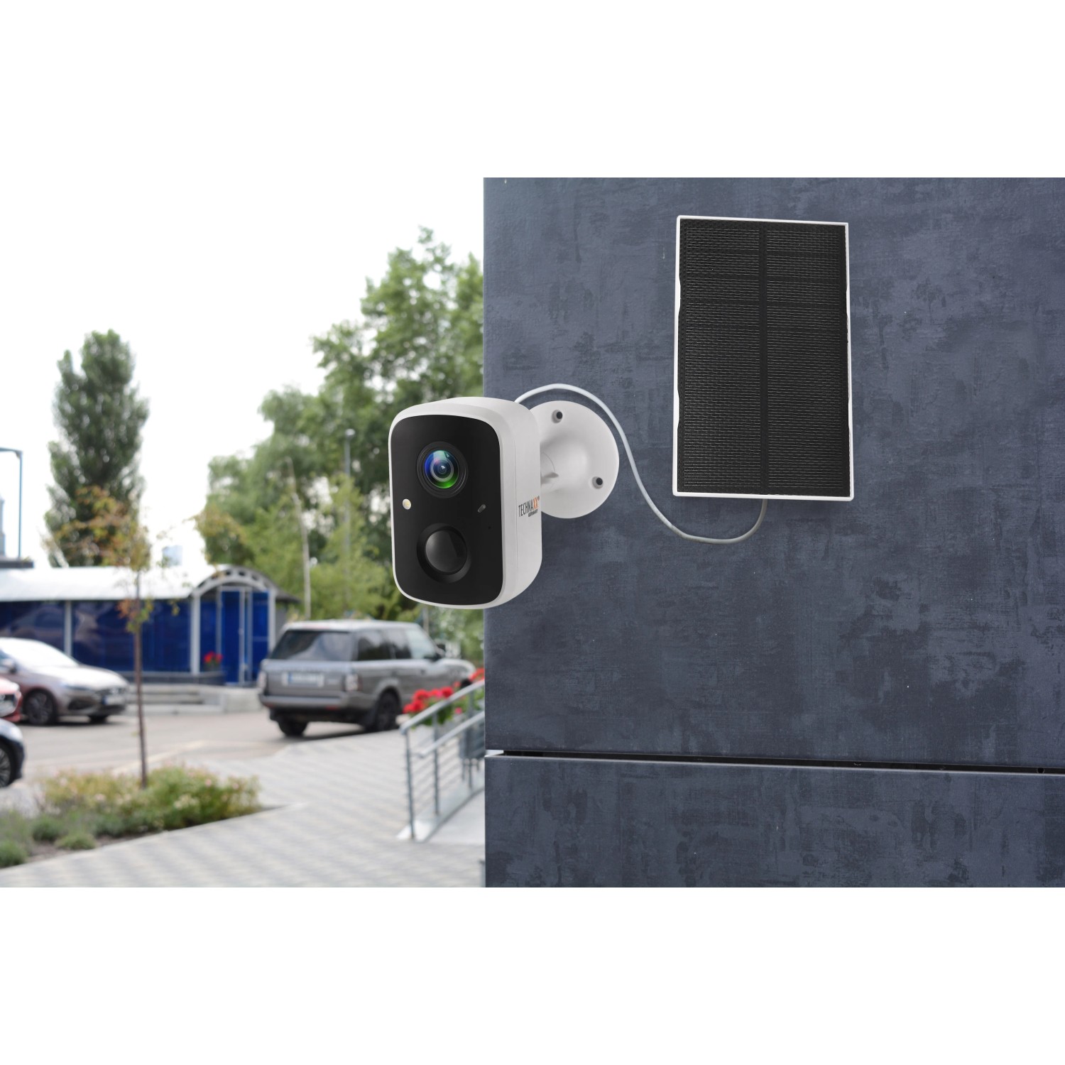Technaxx Outdoor-Kamera TX-244 Solar mit Solarpanel an grauer Wand. Überwachungskamera für Aussen.