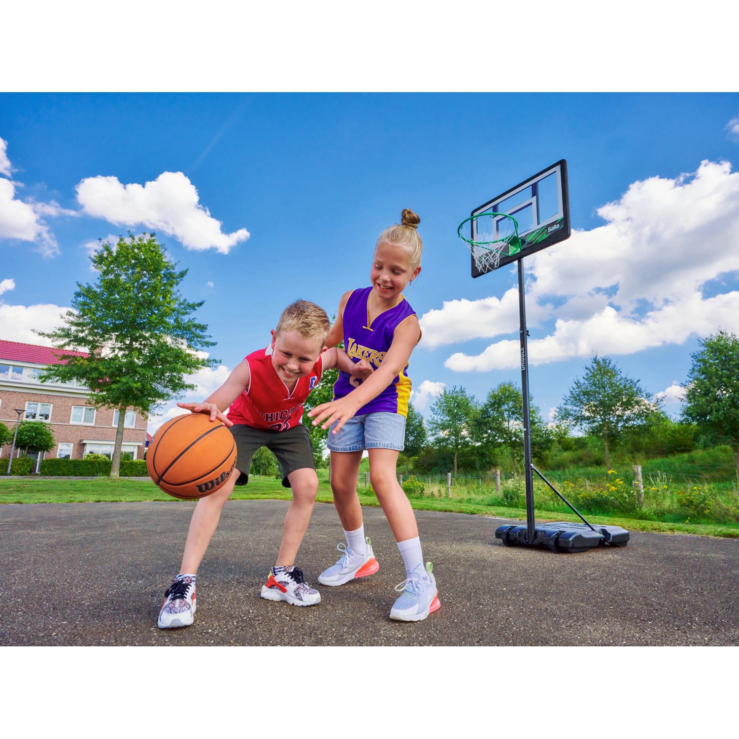 Kinder spielen mit dem Salta Basketballständer Dribble, höhenverstellbar für junge Basketball-Fans.