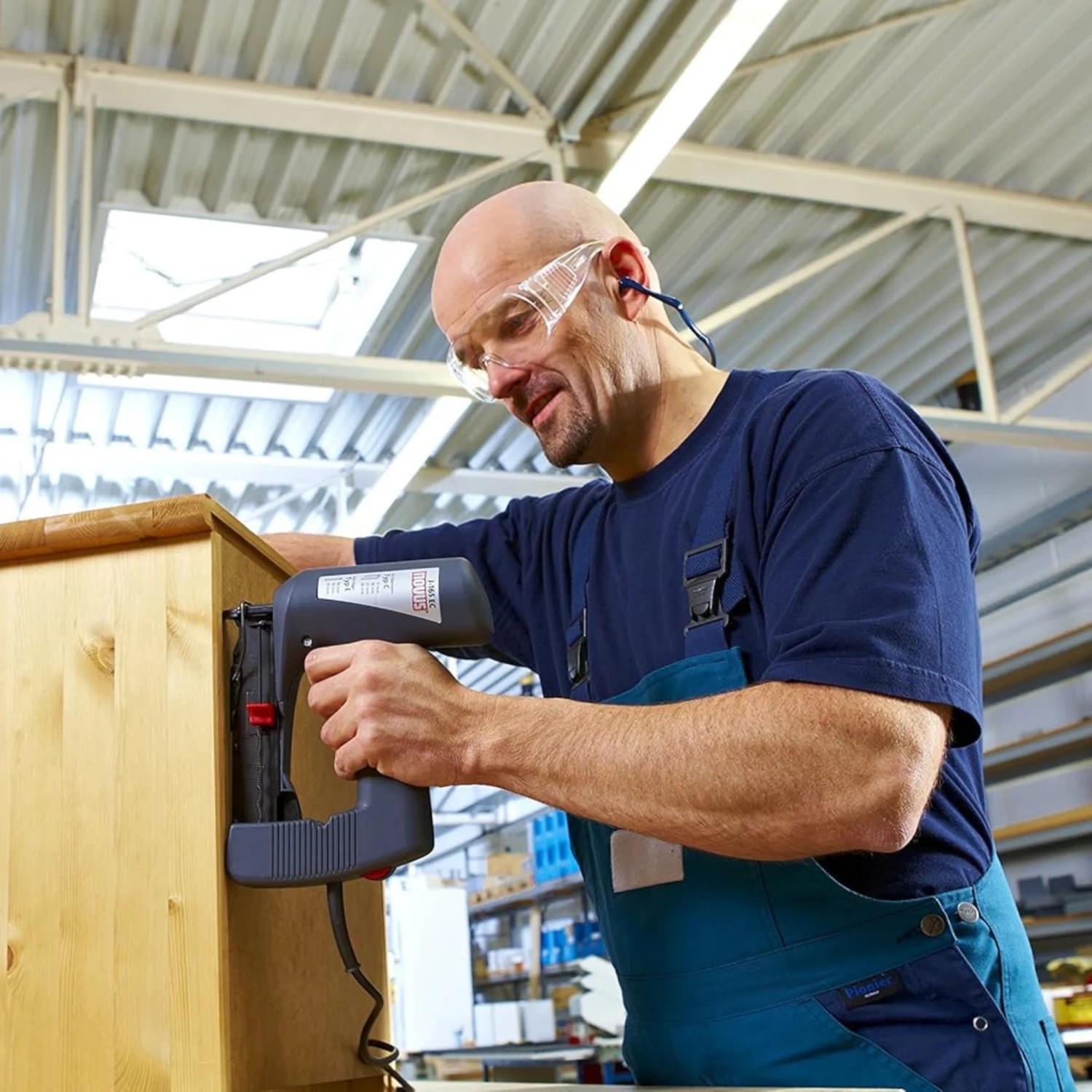 Handwerker befestigt Holz mit Novus Elektrotacker J-165 Panel. Zubehör für Tacker.