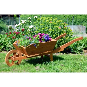 Große, dunkelbraune Pflanz-Schubkarre aus Holz, bepflanzt mit bunten Blumen im Garten.