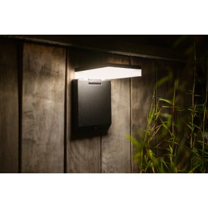 Schwarze, eckige Lutec Solar-LED-Außenleuchte Moze mit Bewegungsmelder an Holzwand.