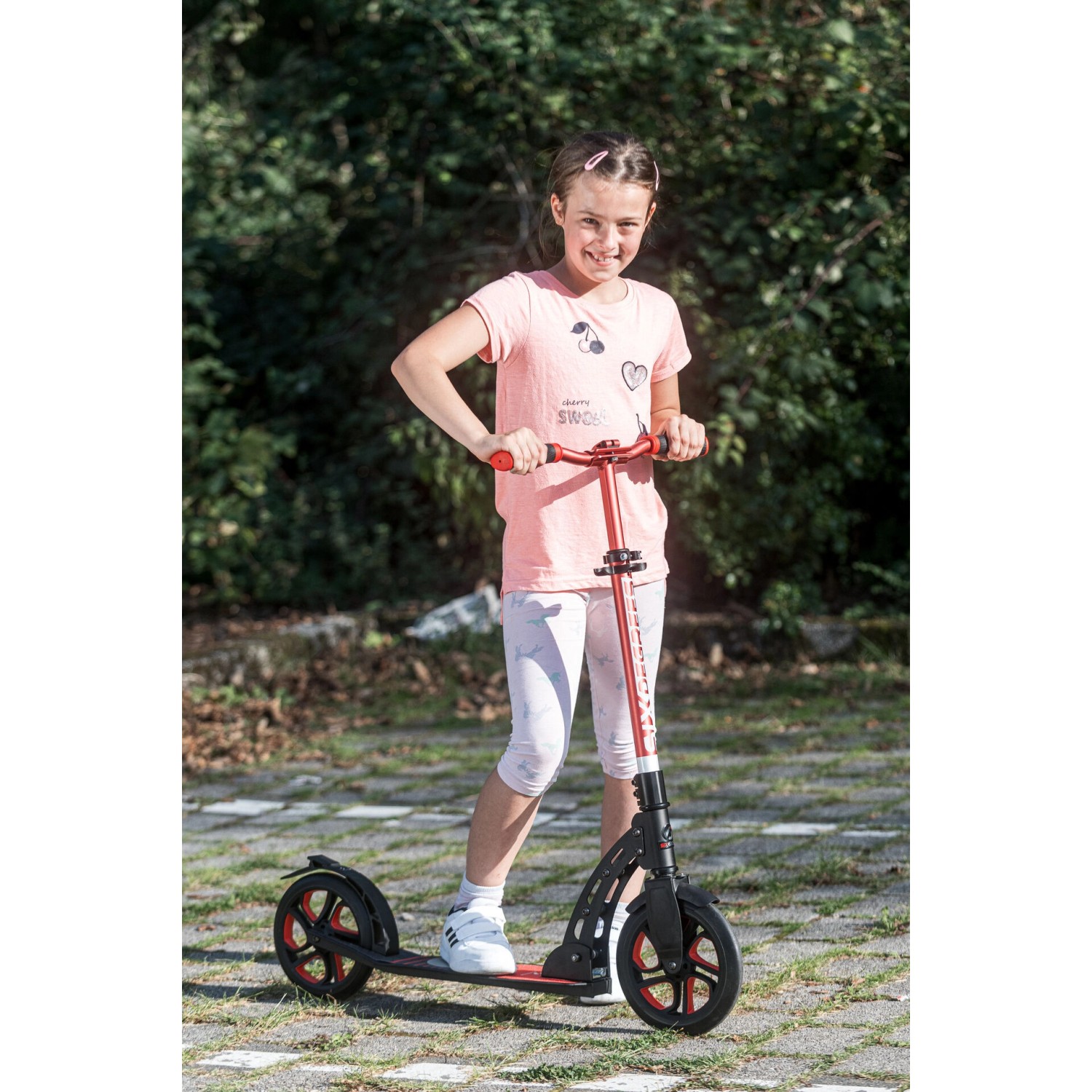 Mädchen auf rotem Six Degrees Aluminium Scooter mit Klappmechanismus und Ständer.