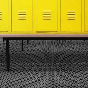Graue KARAT Hygienematte 90x250 cm für Barfußzonen vor gelben Spinden.