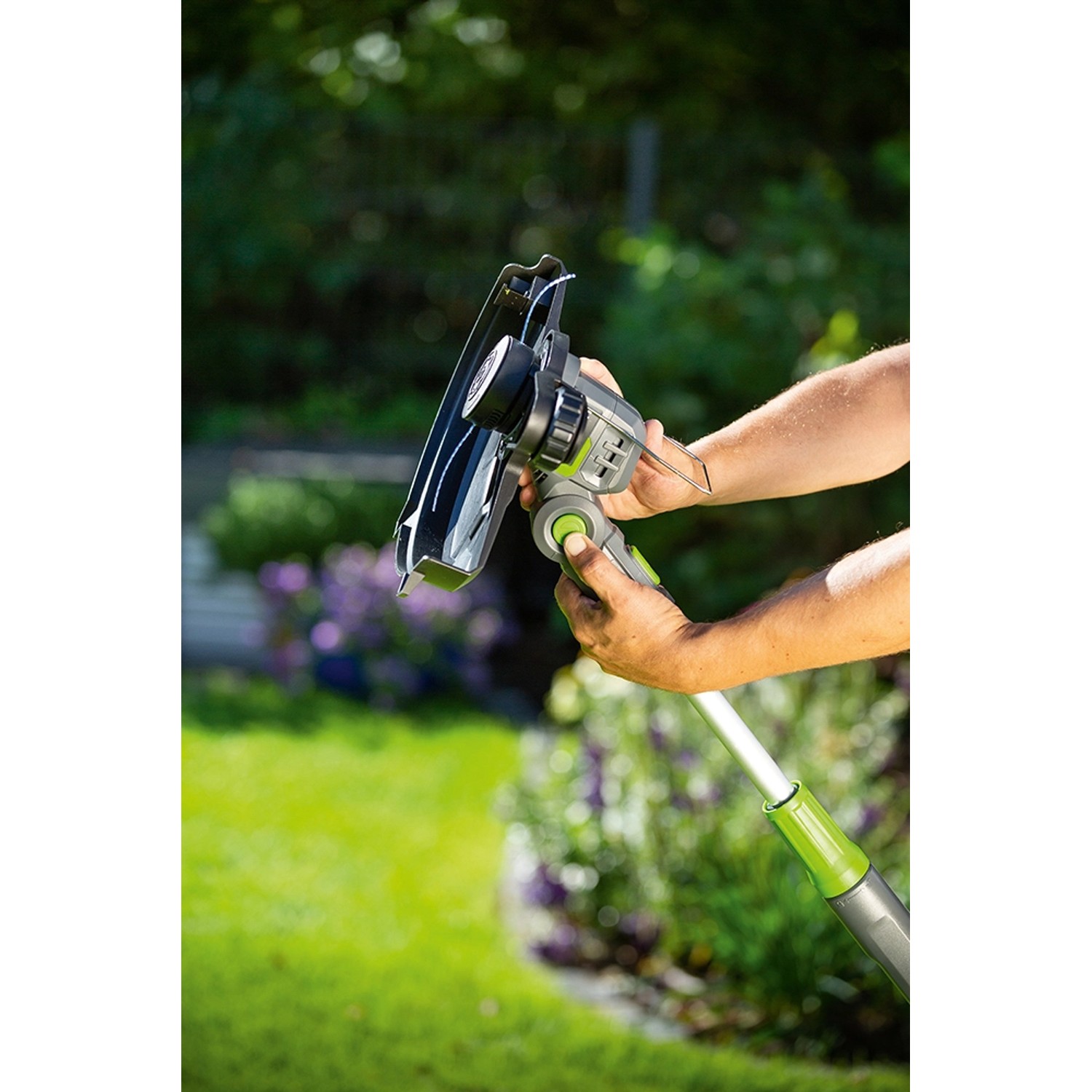 LUX Akku-Rasentrimmer A-RT-20/25 in Nutzung mit Pflanzenschutzbügel und Teleskopstiel.