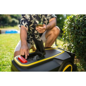 Kärcher RCX 4 Mähroboter mit geöffnetem Fach, bedient von einer Person mit Smartphone im Garten.