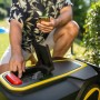 Kärcher RCX 4 Mähroboter mit geöffnetem Fach, bedient von einer Person mit Smartphone im Garten.