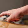 Fiskars Universalmesser CarbonMax™ schneidet Karton. Messer mit einziehbarer Klinge und orangefarbenem Griff.