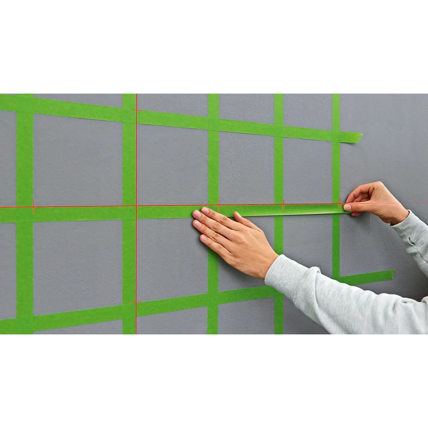 Bosch Quigo Plus Kreuzlinienlaser mit Stativ im Einsatz: Ausrichten von Markierungen an einer Wand.