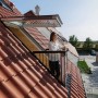 Velux Cabrio Dachfenster geöffnet: Frau steht auf kleinem Dachbalkon mit rotem Ziegeldach.