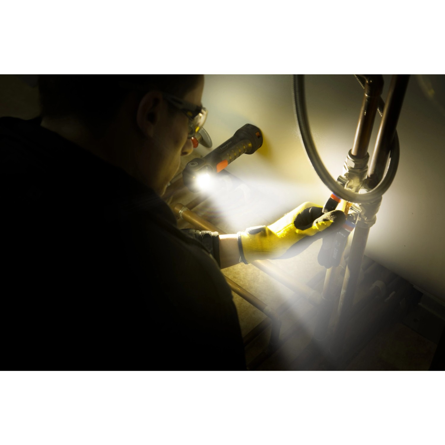 Handwerker mit Energizer Hardcase Arbeitslampe bei Reparaturarbeiten an Rohren.