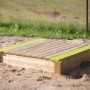 Wendi Toys Sandkasten mit Holzabdeckung und Sitzfläche, aus FSC®-Holz.