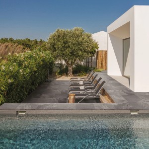 Terrasse mit dunklen Feinsteinzeug Schiefer Black Platten am Pool, Liegen im Hintergrund.