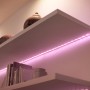 WiZ LED-Strip mit pinkfarbenem Licht auf einem Regal, smarte Beleuchtung für Zuhause.