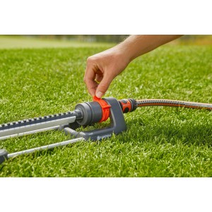Gardena Viereckregner Aqua M in Nutzung: Hand justiert Regner auf Rasenfläche.