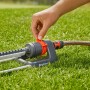 Gardena Viereckregner Aqua M in Nutzung: Hand justiert Regner auf Rasenfläche.
